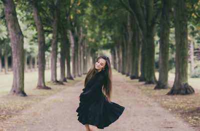 Woman standing by tree trunk in forest