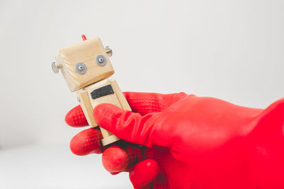 Close-up of hand holding toy against white background