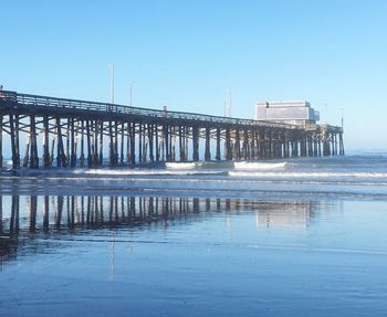 Pier over sea against clear blue sky