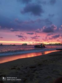 Scenic view of beach against dramatic sky during sunset