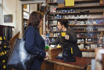 Female holding name tag while standing with customer at shoe store