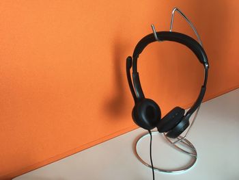 High angle view of headphones on hook by orange wall