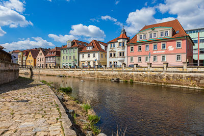 Buildings by river against sky