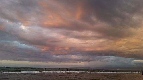 Scenic view of sea against dramatic sky during sunset