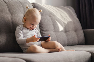 Boy using phone while sitting on sofa at home