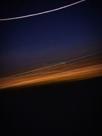 Light trails on road against sky at night