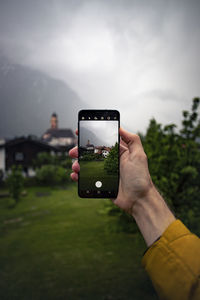 Midsection of man holding smart phone against sky
