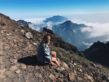 Man sitting on rock against mountain range