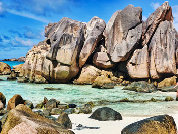 Scenic view of rocks by sea against sky