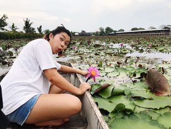 Young woman sitting on plant against sky