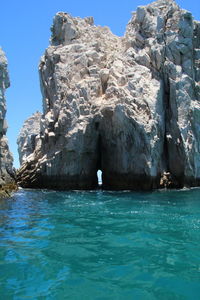 Rock formations in sea against blue sky