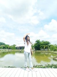 Full length of woman standing by lake against sky