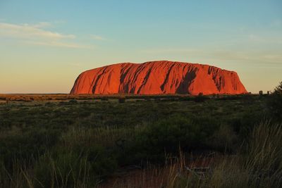 Rock formations on field against sky during sunset