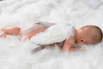 High angle view of cute baby girl lying over fur blanket on bed at home