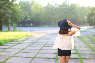 Rear view of woman wearing hat standing against trees