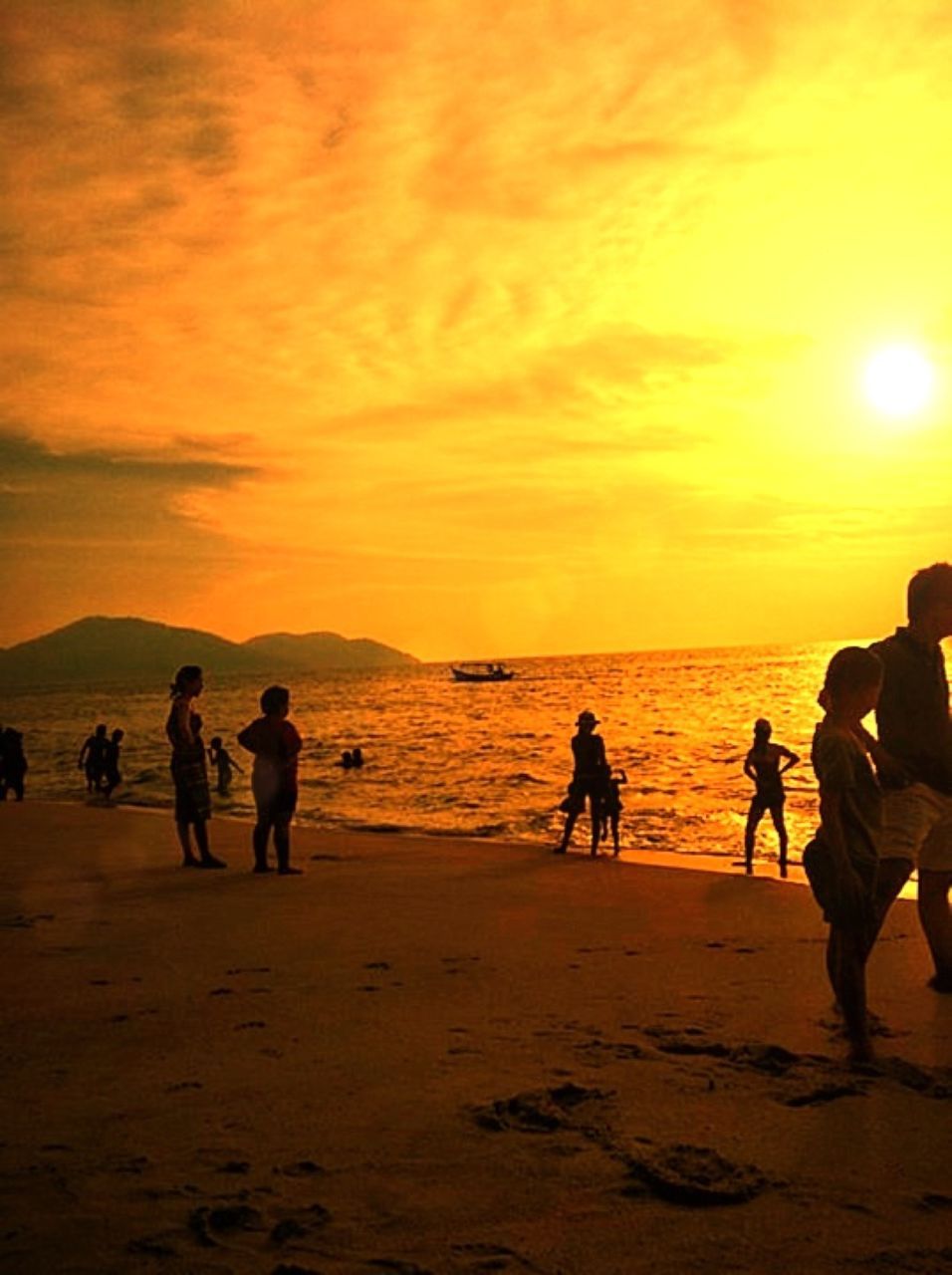 sunset, sea, beach, water, scenics, beauty in nature, sky, silhouette, orange color, sun, shore, vacations, tranquil scene, leisure activity, horizon over water, tranquility, lifestyles, large group of people, idyllic