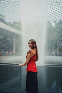 Portrait of woman standing by fountain outdoors