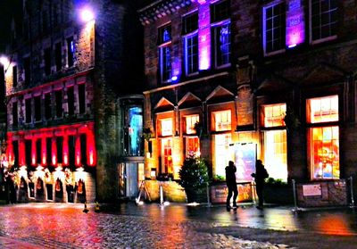 Man walking on illuminated street amidst buildings at night