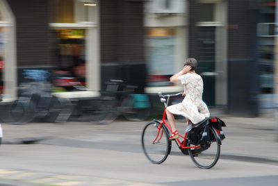 Blurred motion of man riding bicycle on city street