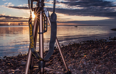 Nikon d750 with visible shoulder strap and sunset beaming through the tripod