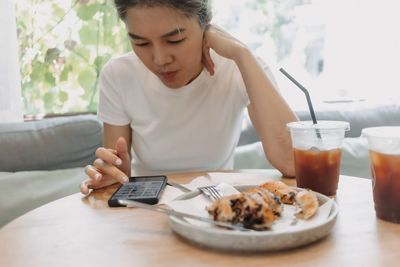Young woman using mobile phone while sitting on table