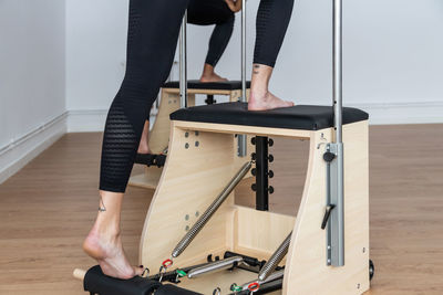 Unrecognizable sportspeople balancing on pilates chairs while doing exercises during workout in bright gym