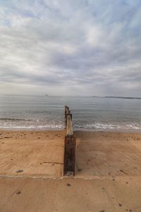 Wooden posts on beach against sky