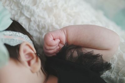 Cropped image of baby girl lying on bed