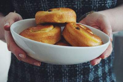 Midsection of woman holding croissant in bowl