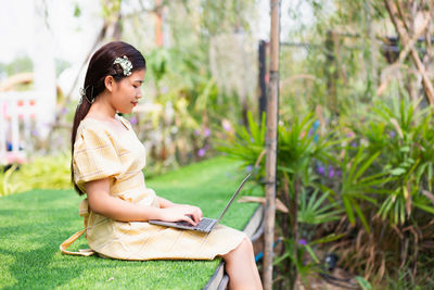 Side view of a smiling young woman sitting outdoors