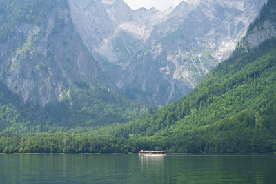 Small boat sailing on alpine lake surrounded by high mountains , konigssee, germany