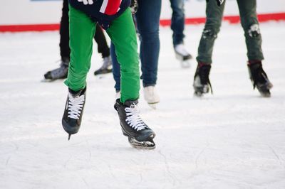 Low section of people ice-skating on rink