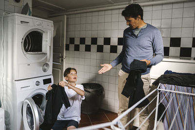 Son and father doing chores in utility room