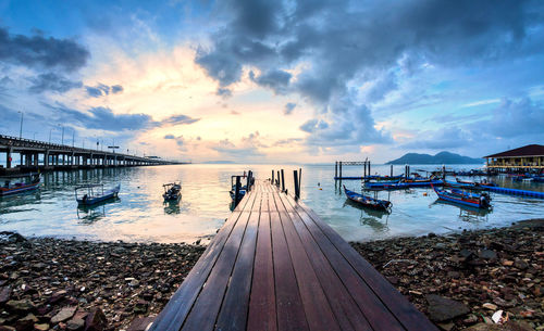 Pier over sea against sky during sunset