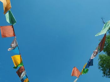 Low angle view of flags against clear blue sky