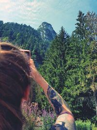 Rear view of person against plants and trees against sky