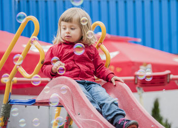 Portrait of cute girl sitting on slide at playground
