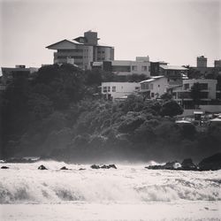 Buildings by sea against sky