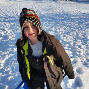 Portrait of boy wearing knit hat standing on snow covered field
