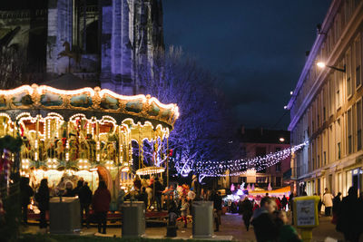 People at amusement park against sky at night