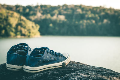 Close-up of shoes on rock by lake