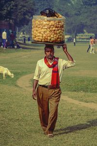 Full length of man selling food while walking on grassy field at park
