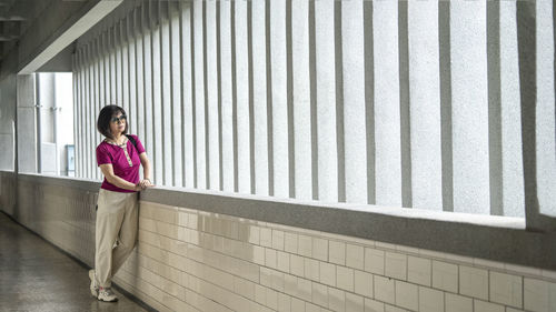 Side view of woman standing against wall
