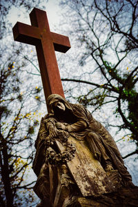 Low angle view of cross statue against trees