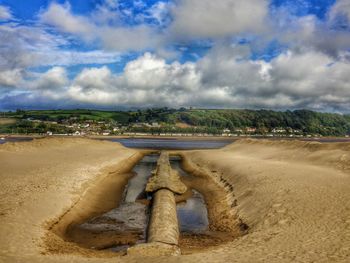 Scenic view of beach against cloudy sky