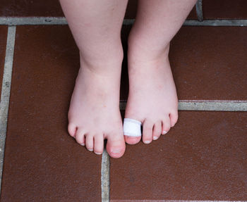 Low section of child with bandage standing on floor