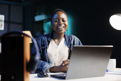 Portrait of smiling woman using laptop at office