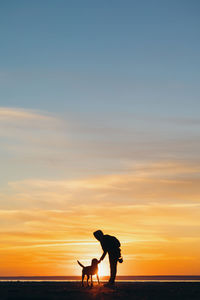 The silhouette of a man against the sunset with a dog.  nature walk