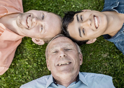 Close-up of happy three generation males lying on grass
