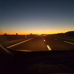 Car moving on highway against clear sky during sunset